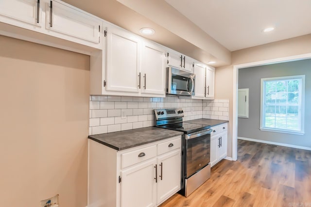 kitchen with appliances with stainless steel finishes, backsplash, light hardwood / wood-style floors, and white cabinetry