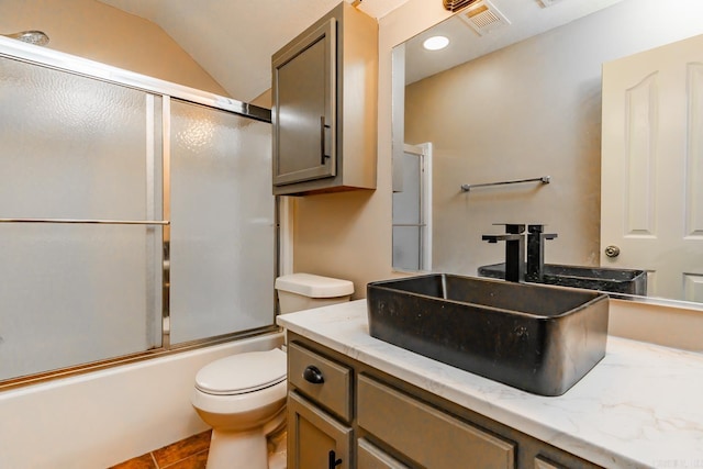 full bathroom featuring tile patterned floors, vanity, vaulted ceiling, enclosed tub / shower combo, and toilet