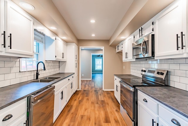 kitchen featuring a wealth of natural light, white cabinetry, sink, and appliances with stainless steel finishes