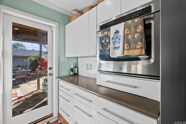 kitchen featuring white cabinets, ornamental molding, and stainless steel oven