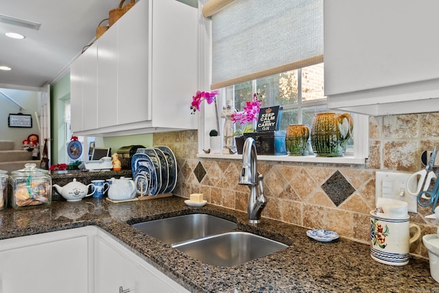 kitchen featuring white cabinets, dark stone counters, and sink