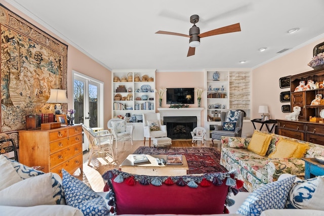 living room featuring wood-type flooring, built in features, ceiling fan, and crown molding