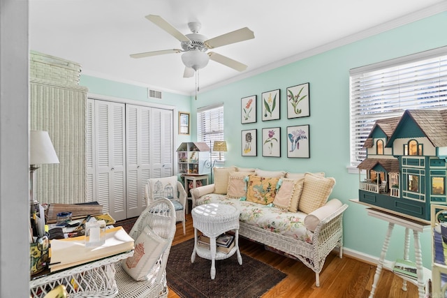 living room with hardwood / wood-style flooring, ceiling fan, and crown molding