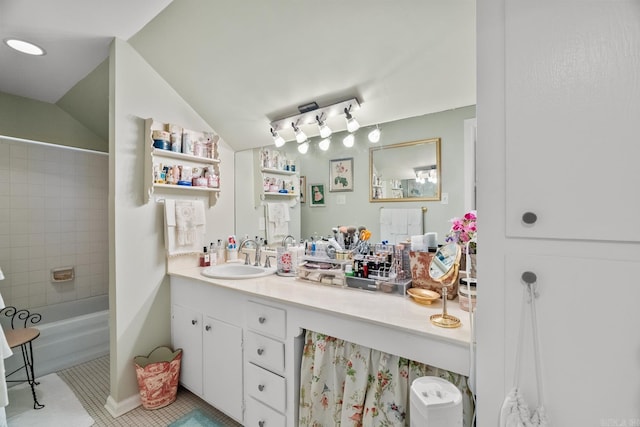 bathroom with tile patterned flooring, vanity, vaulted ceiling, and tiled shower / bath