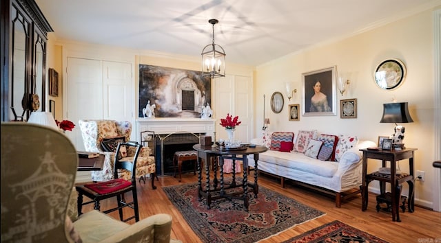 living room featuring wood-type flooring, crown molding, and a notable chandelier