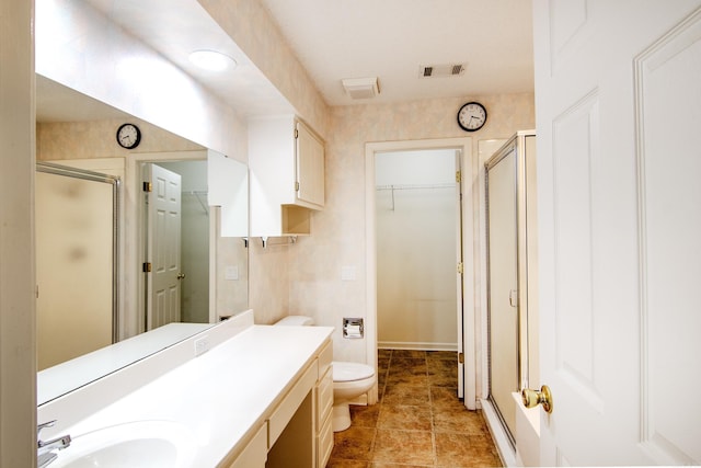 bathroom with tile patterned flooring, a shower with door, vanity, and toilet