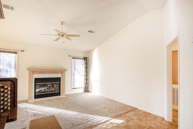 unfurnished living room with a textured ceiling, light colored carpet, vaulted ceiling, ceiling fan, and a fireplace