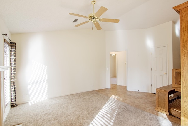 empty room with plenty of natural light, ceiling fan, light carpet, and high vaulted ceiling