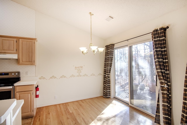 interior space featuring stainless steel electric range oven, light brown cabinets, light hardwood / wood-style flooring, a chandelier, and decorative light fixtures