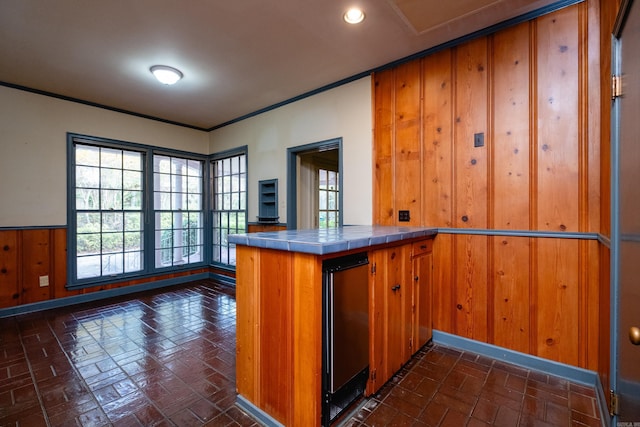 kitchen with tile countertops, wood walls, and kitchen peninsula