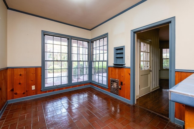 unfurnished room with ornamental molding, heating unit, a healthy amount of sunlight, and wood walls