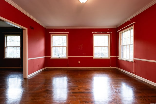 empty room with dark hardwood / wood-style floors, crown molding, and a healthy amount of sunlight