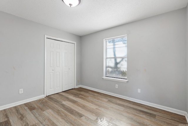 unfurnished bedroom featuring light wood-type flooring, a textured ceiling, and a closet