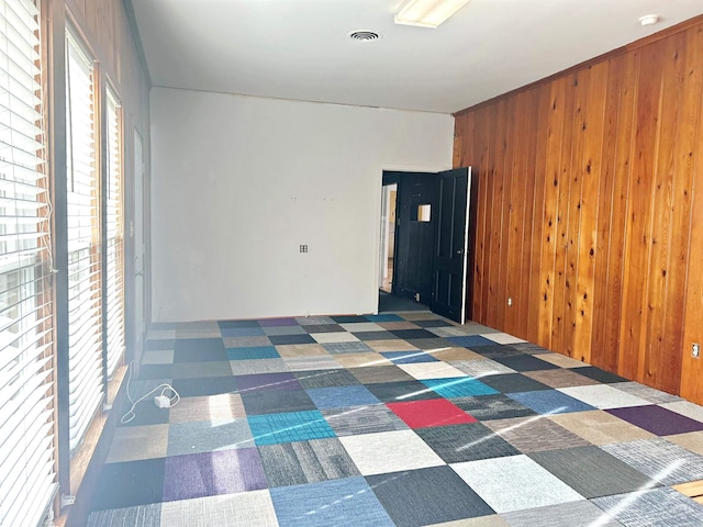 unfurnished room featuring wood walls and dark carpet