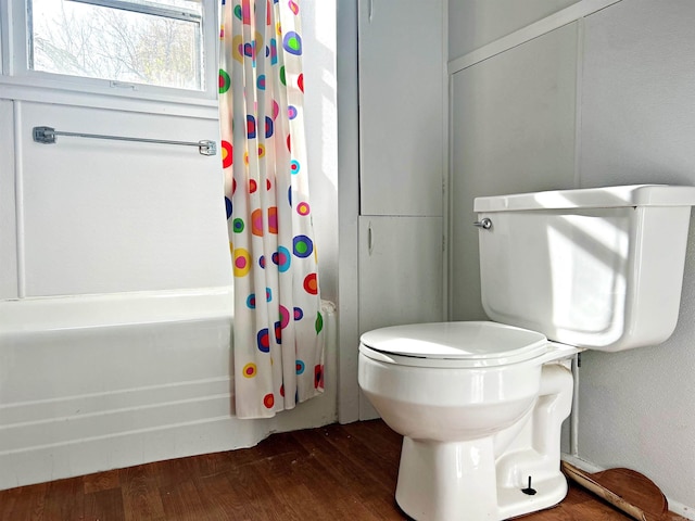 bathroom featuring toilet, hardwood / wood-style floors, and shower / tub combo with curtain