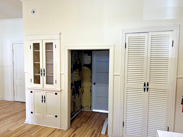 hall with light hardwood / wood-style floors and ornamental molding