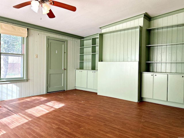 interior space with wood walls, ceiling fan, and dark hardwood / wood-style floors