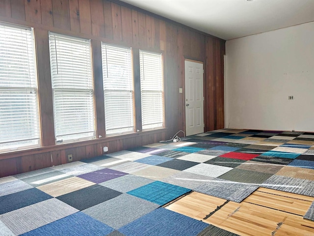 unfurnished room with wooden walls, a healthy amount of sunlight, and hardwood / wood-style flooring