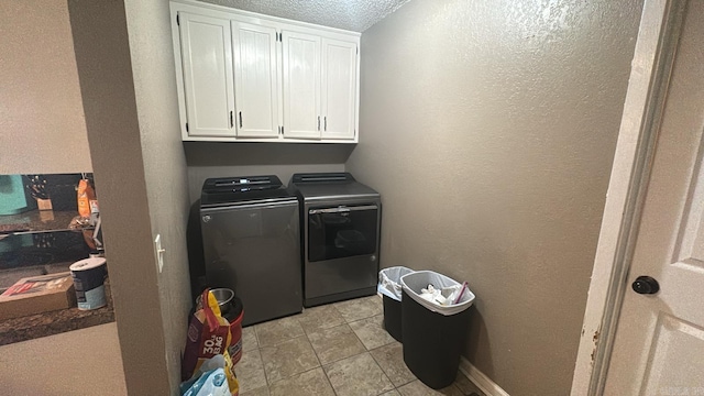 laundry area with cabinets, light tile patterned floors, a textured ceiling, and separate washer and dryer