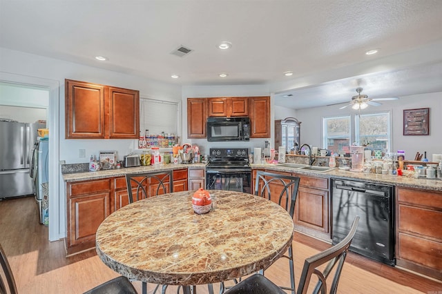 kitchen featuring black appliances, ceiling fan, light wood-type flooring, and sink