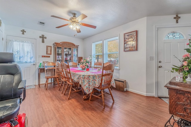 dining area with a textured ceiling, light hardwood / wood-style floors, ceiling fan, and a healthy amount of sunlight