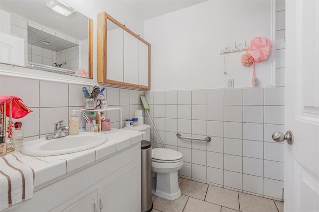 bathroom with tile patterned flooring, vanity, toilet, and tile walls