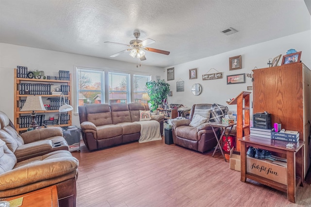 living room with ceiling fan, hardwood / wood-style floors, and a textured ceiling