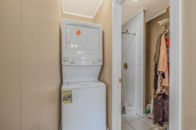 washroom featuring wooden walls, light tile patterned floors, stacked washer and clothes dryer, and ornamental molding