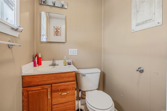 bathroom featuring vanity, wood walls, toilet, and electric panel