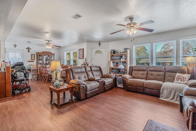 living room featuring ceiling fan, wood-type flooring, and a textured ceiling