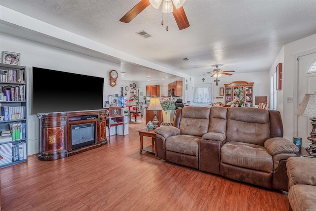 living room with a textured ceiling, hardwood / wood-style flooring, and ceiling fan