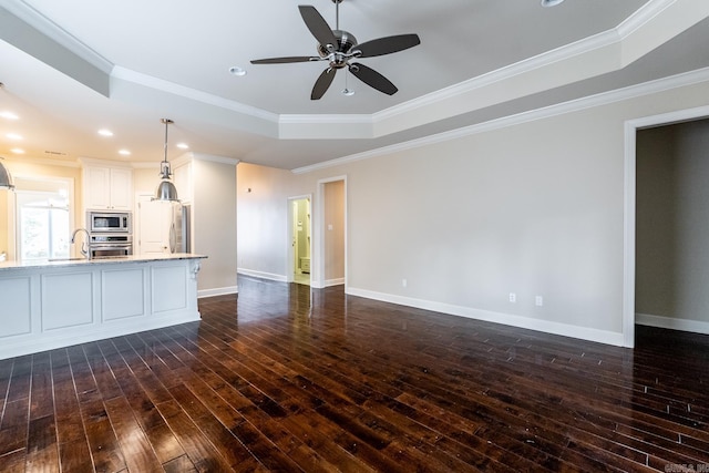 unfurnished living room with dark hardwood / wood-style flooring, a tray ceiling, ceiling fan, and crown molding