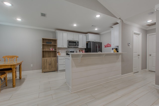 kitchen featuring kitchen peninsula, appliances with stainless steel finishes, a kitchen breakfast bar, crown molding, and white cabinets