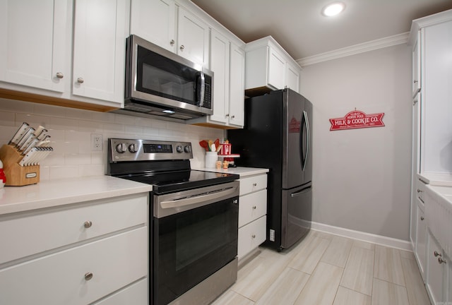 kitchen with white cabinets, decorative backsplash, stainless steel appliances, and crown molding