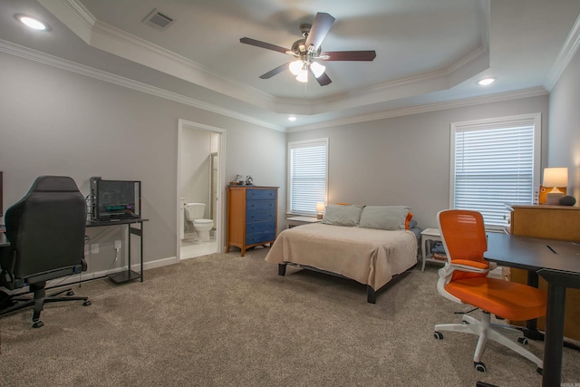 carpeted bedroom with ceiling fan, a raised ceiling, crown molding, and ensuite bath