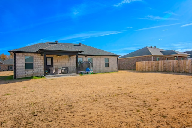 rear view of property with a patio and a trampoline