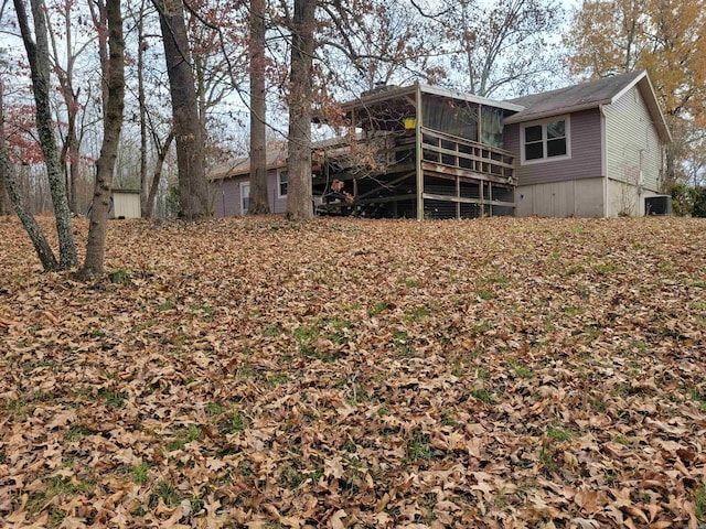 rear view of property with a sunroom, a wooden deck, and central AC