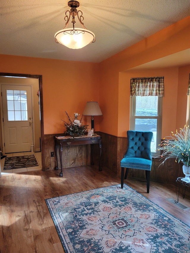 interior space featuring a textured ceiling, hardwood / wood-style flooring, and wooden walls