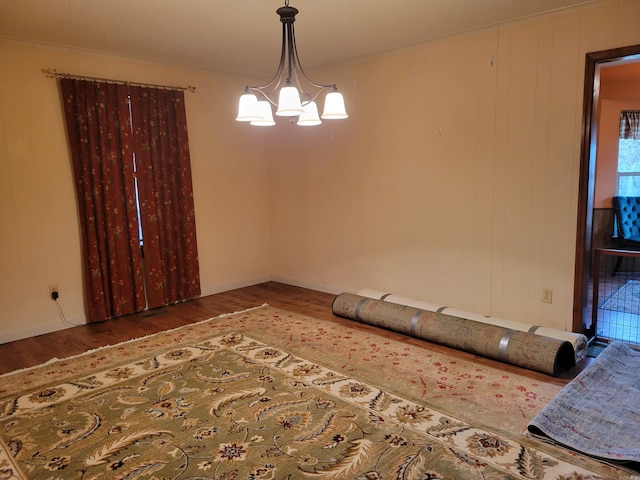 unfurnished room featuring wood-type flooring and a notable chandelier