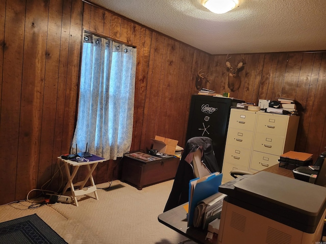 carpeted home office with wooden walls and a textured ceiling