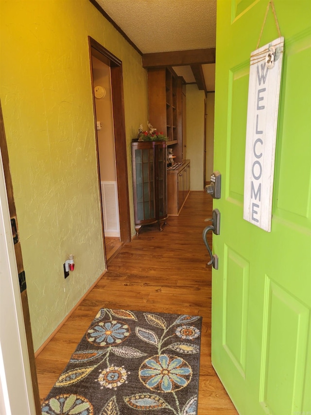 hall featuring wood-type flooring and a textured ceiling