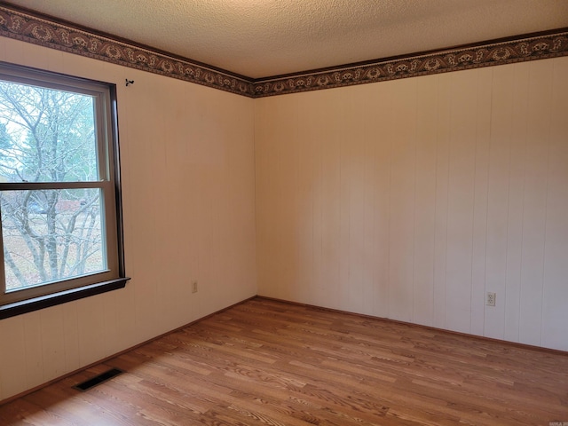 empty room featuring wood walls, a textured ceiling, and hardwood / wood-style flooring