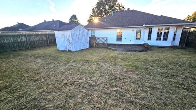 back of house featuring a storage unit and a lawn