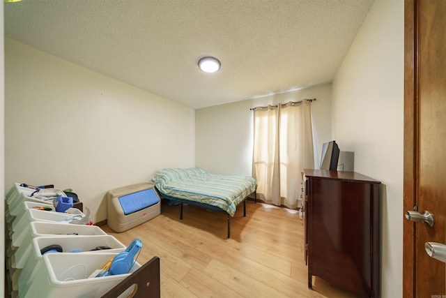 bedroom with light hardwood / wood-style floors and a textured ceiling