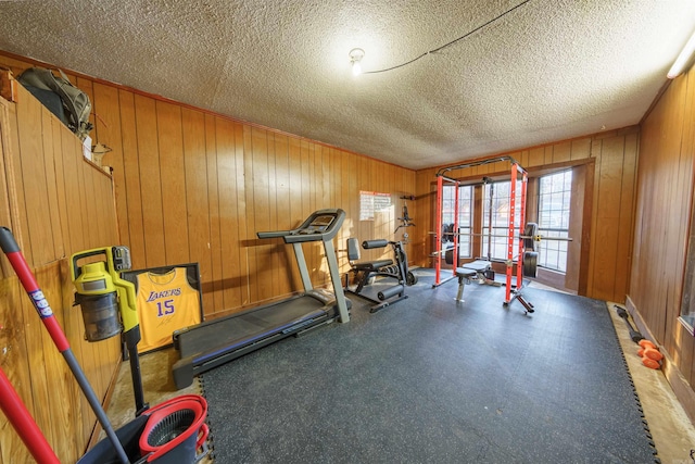 exercise room with a textured ceiling and wooden walls