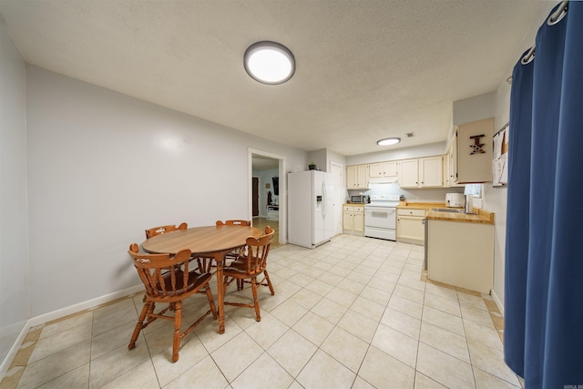 kitchen featuring sink, white appliances, a textured ceiling, and light tile patterned floors