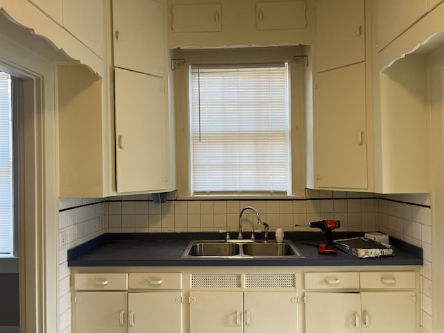 kitchen with decorative backsplash, white cabinetry, and sink