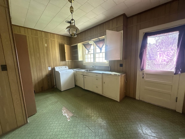laundry room featuring wood walls, cabinets, sink, and washer / clothes dryer