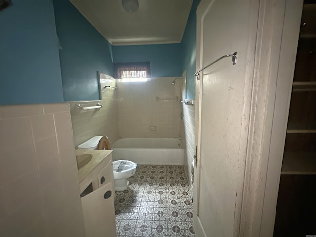 full bathroom with tiled shower / bath, vanity, tile walls, and toilet