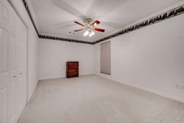 carpeted empty room with ceiling fan and ornamental molding